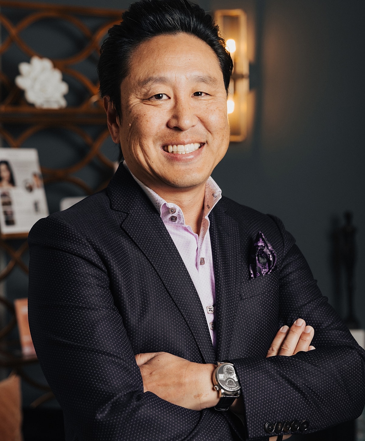 Smiling man in a suit with crossed arms.