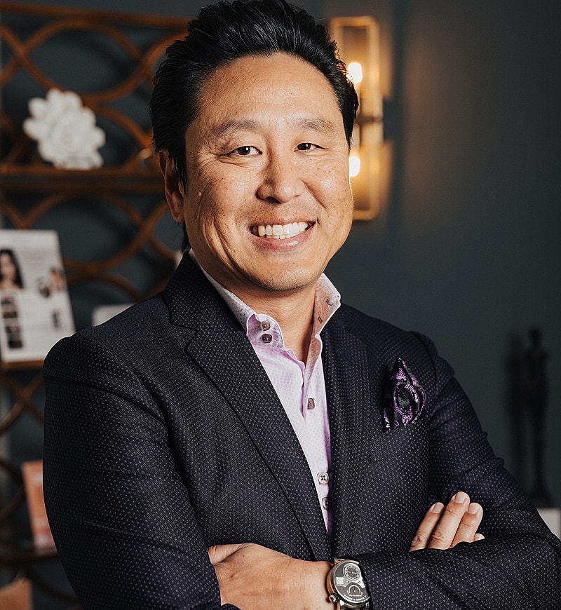 Smiling man in business attire with crossed arms.