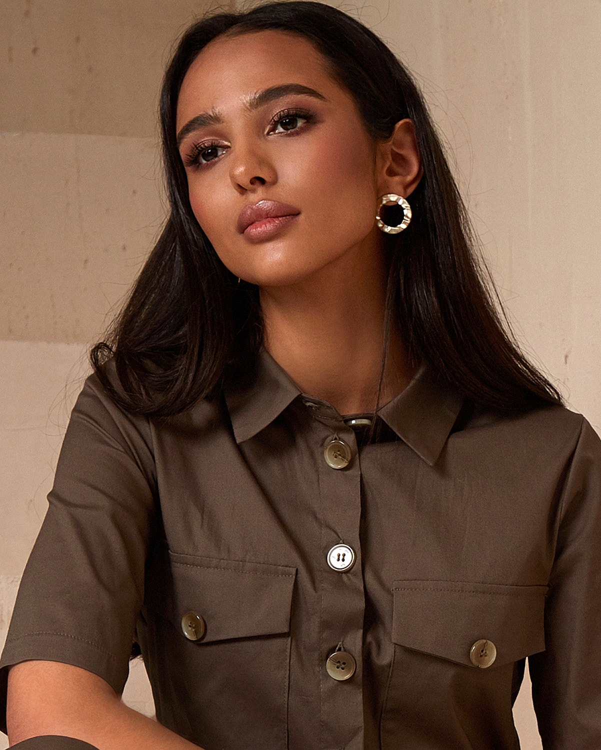 Woman in brown shirt with elegant earrings.