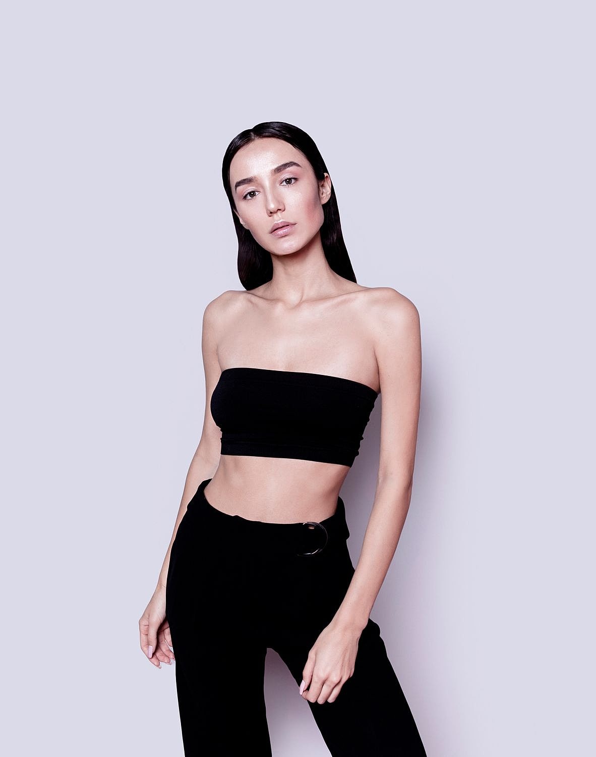 Model posing in black outfit against plain background.