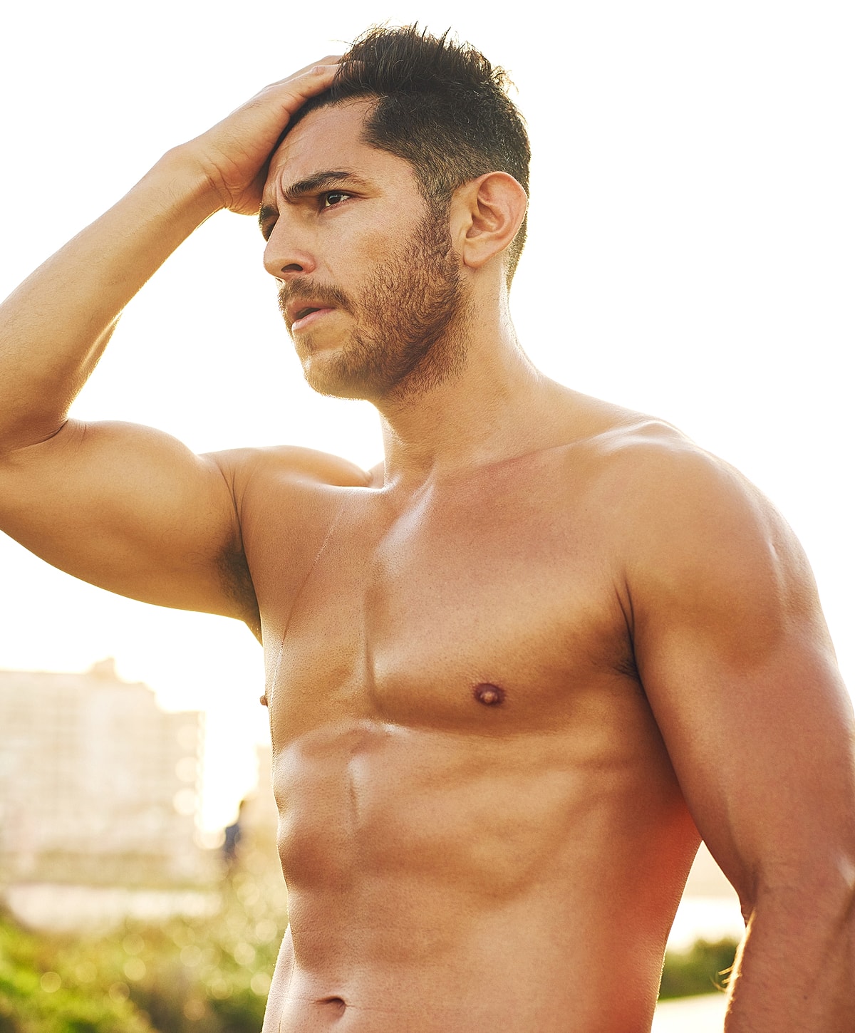Man with short hair, sunlit beach background.