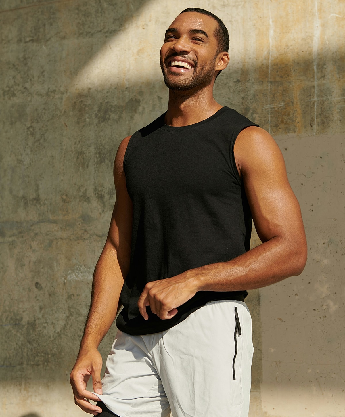 Smiling man in black tank top outdoors.