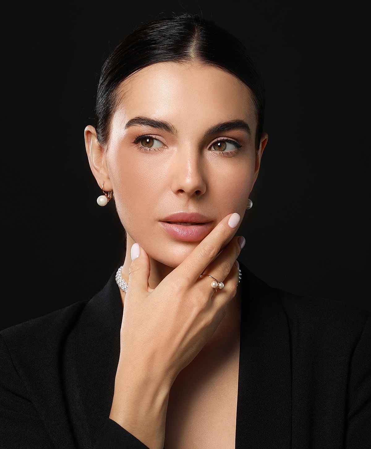 Woman with jewelry posing against black background.