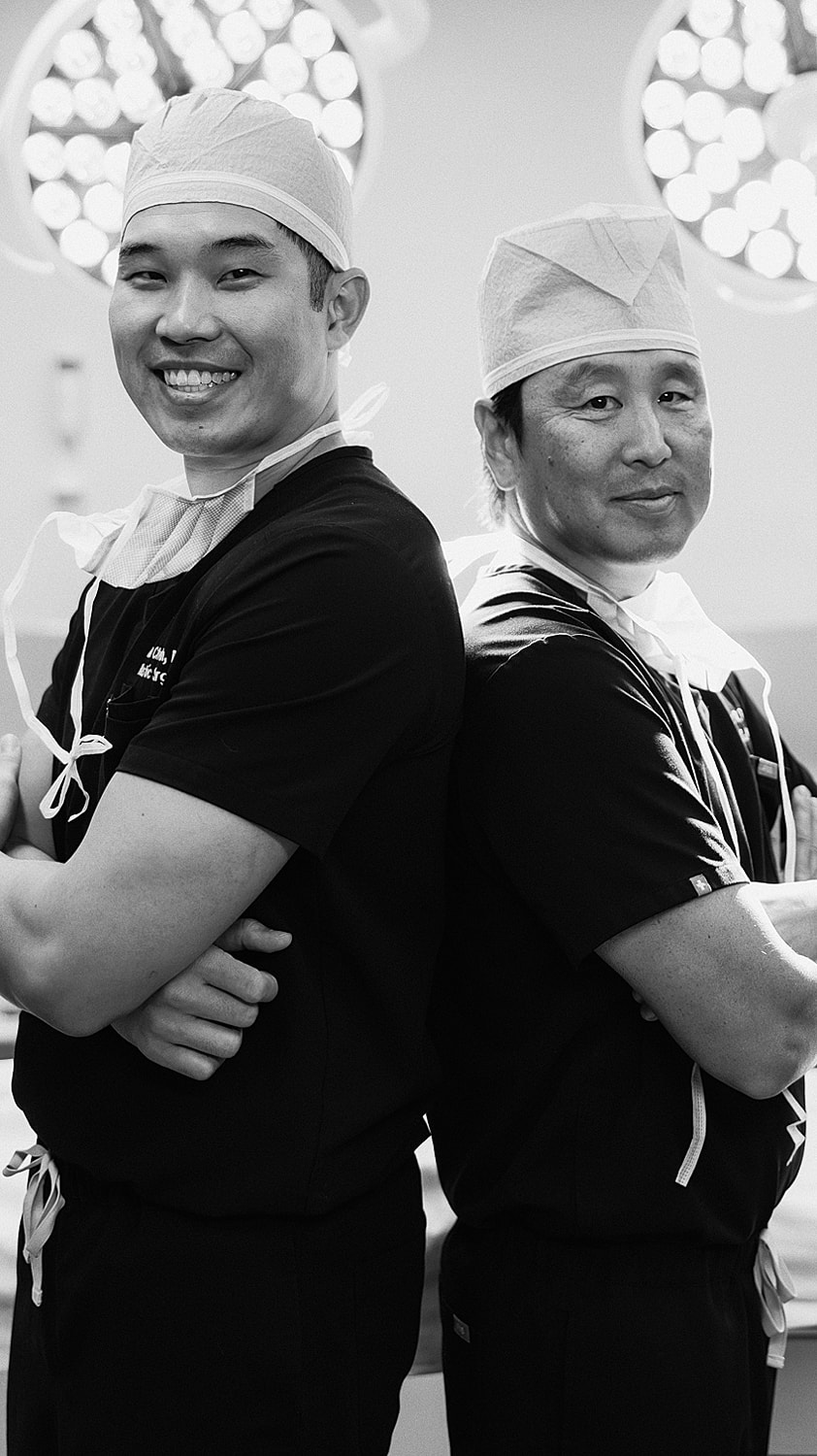 Surgeons smiling in operating room attire.