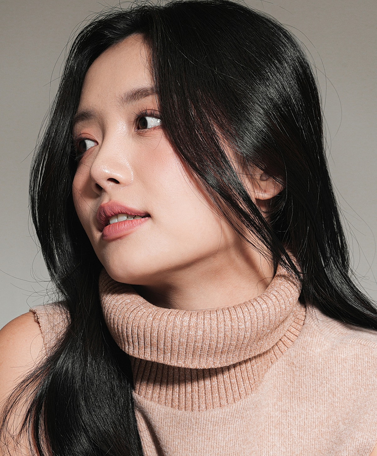 Woman with long black hair in turtleneck sweater.