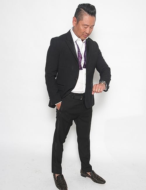 Man in suit checking watch, stylish pose.