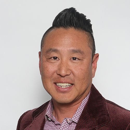 Man with stylish haircut and patterned jacket.