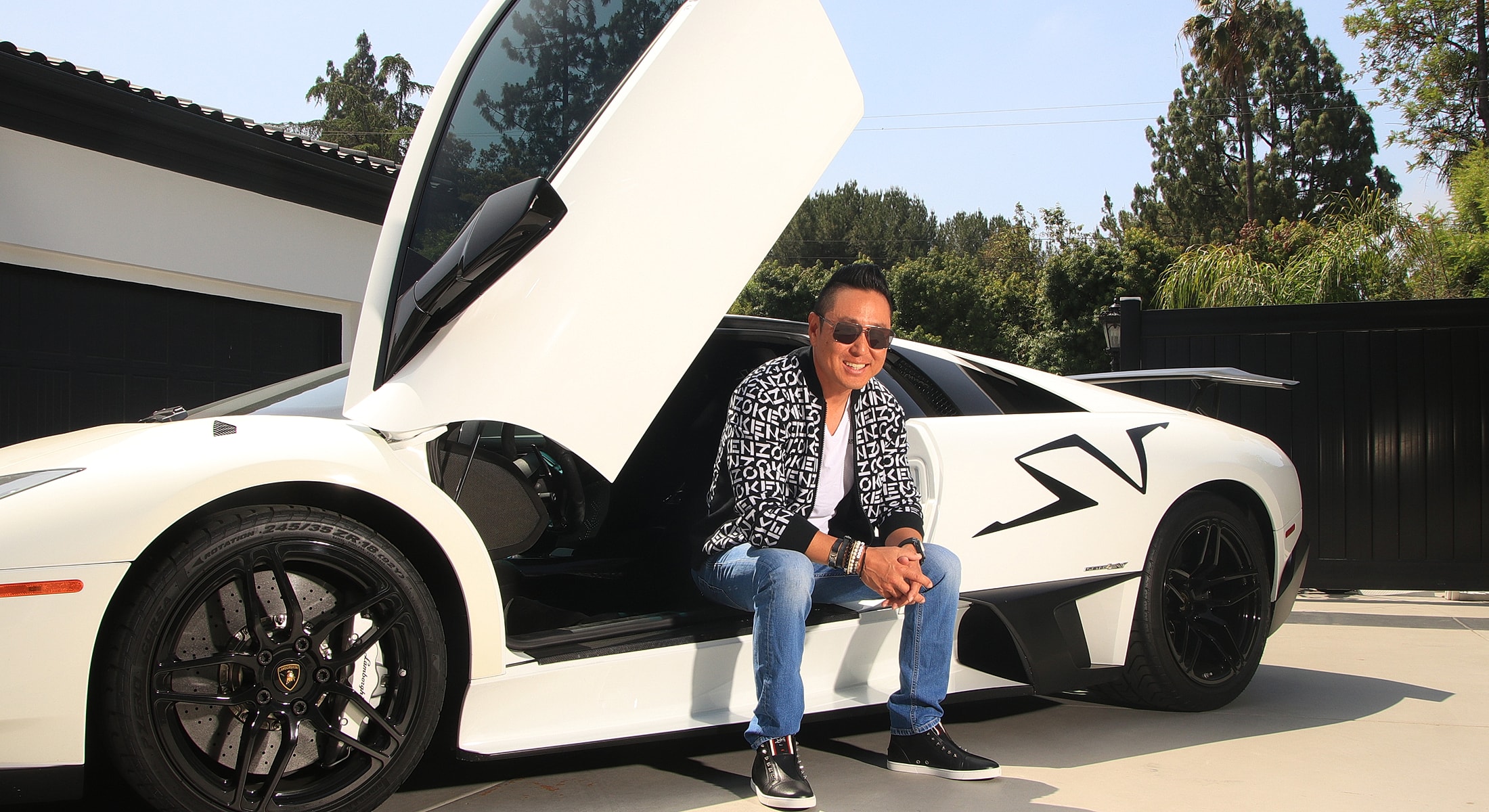 Person sitting by a white Lamborghini with open door.