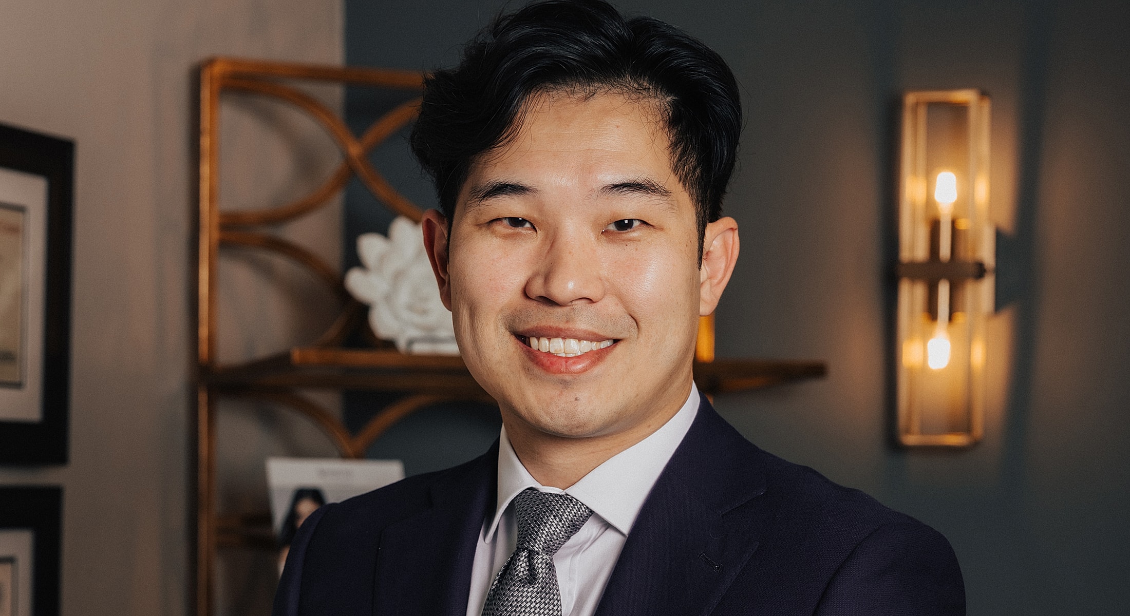 Smiling man in a suit against a stylish background.