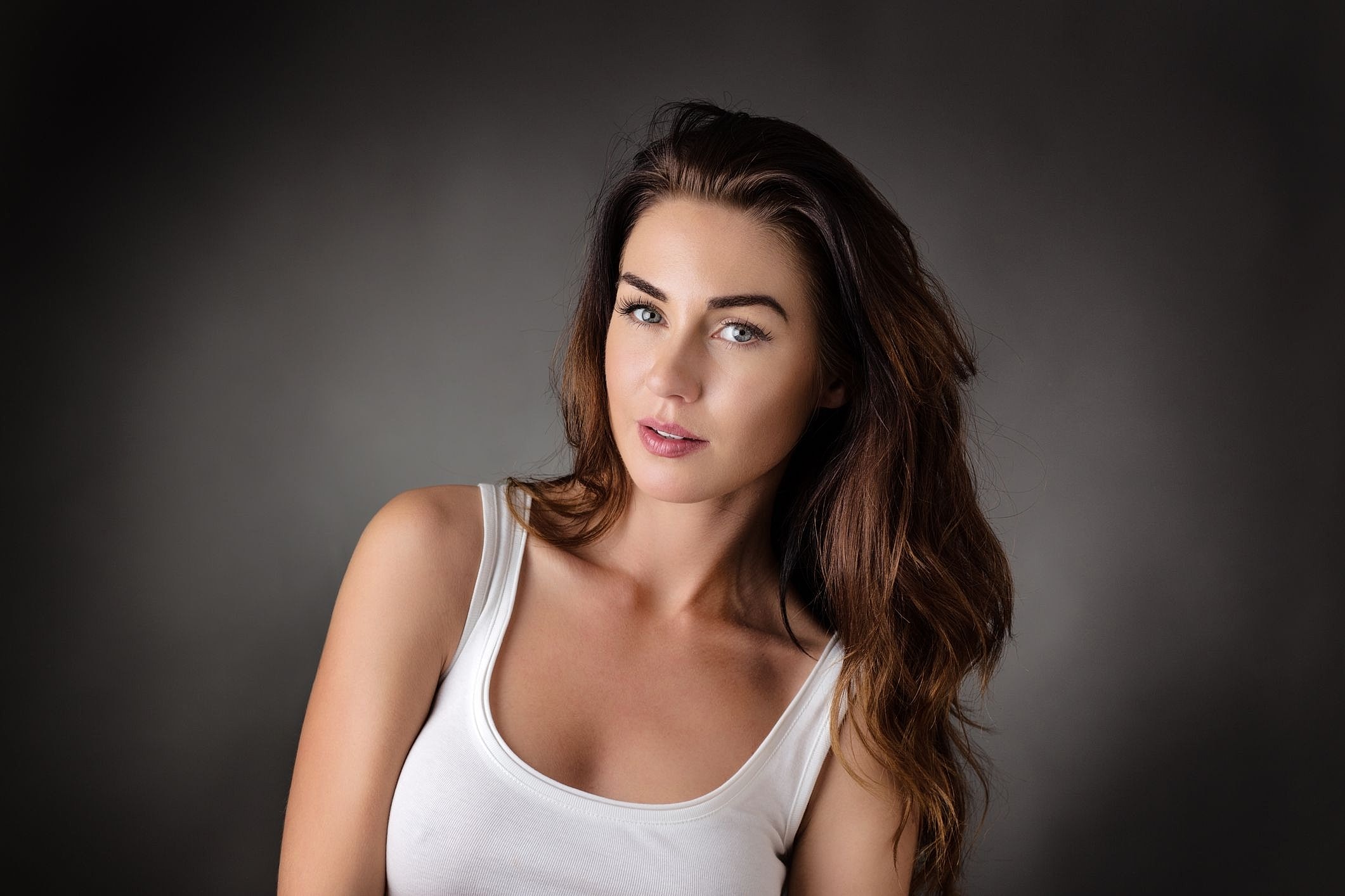 Woman with long hair in white tank top.
