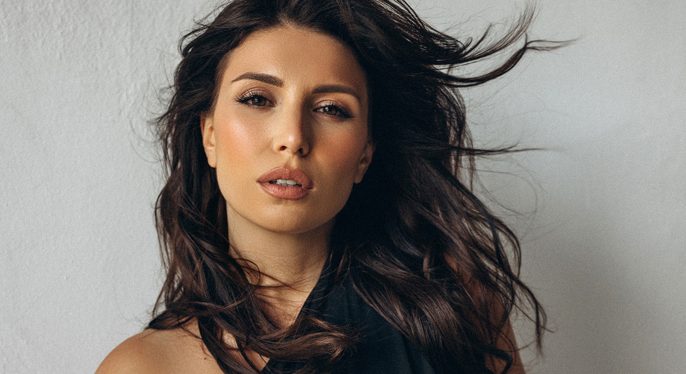 Woman with flowing hair against a neutral background.