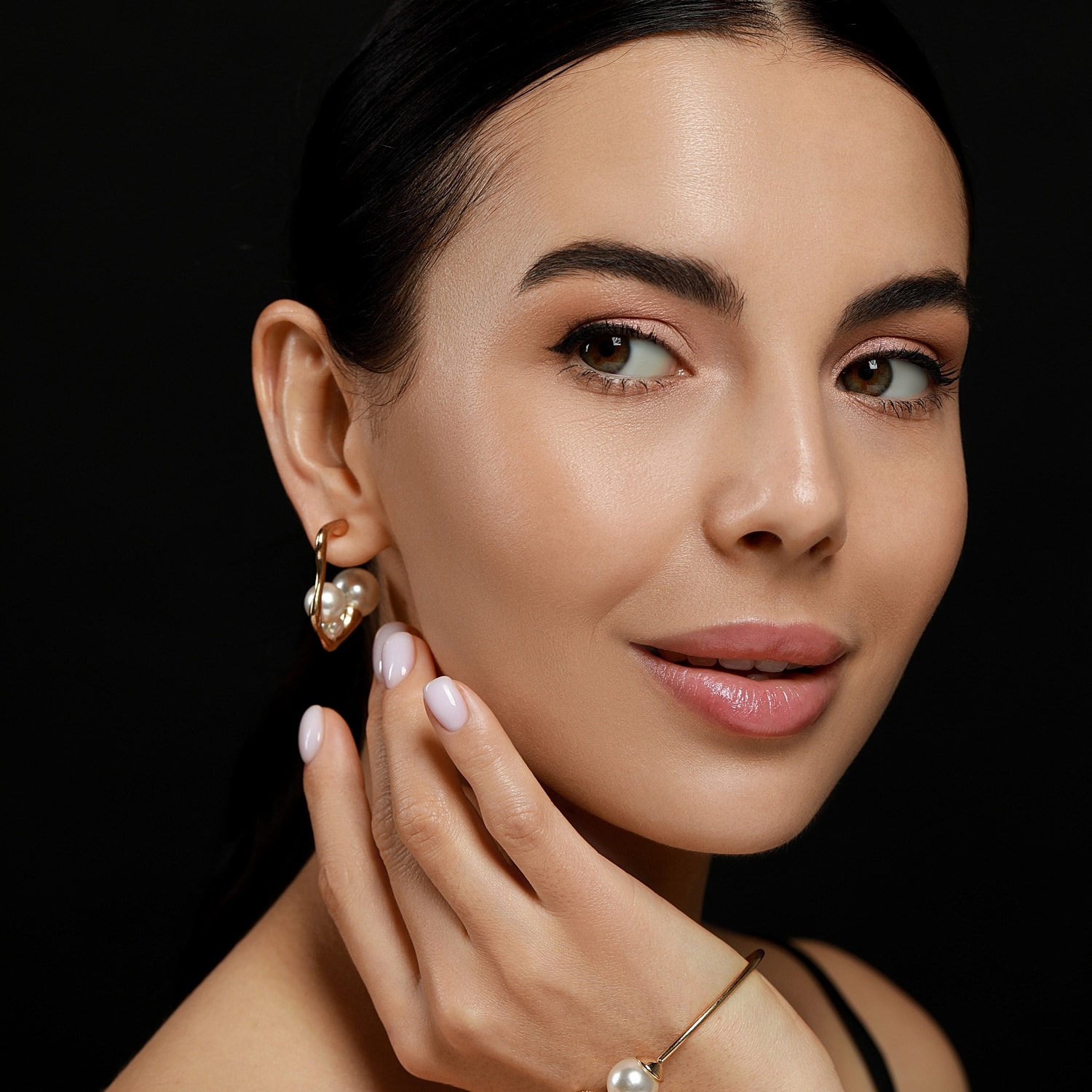 Woman with earrings and natural makeup on black background.